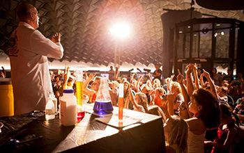 Mad scientist on stage with kids sitting on the floor
