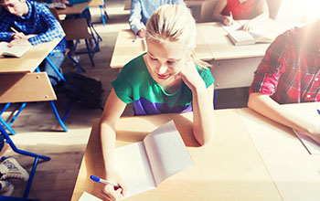 Students sitting at their desks writing in a notebook