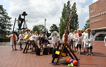 kids in lab coats playing with 2 large catapults