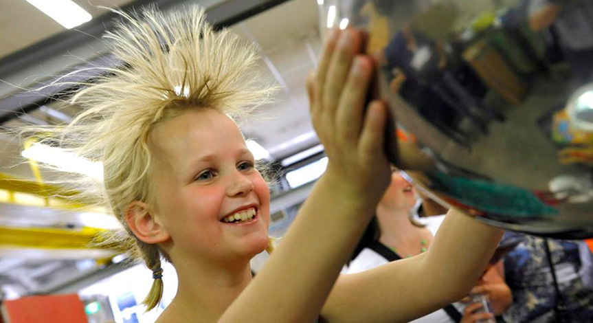 Blond girl touching van de graaff causing her hair to stand