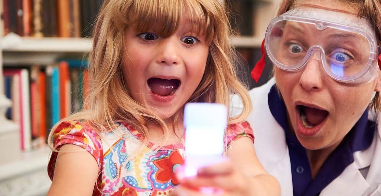 Excited girl and Mad Scientist looking at beaker filled with white liquid