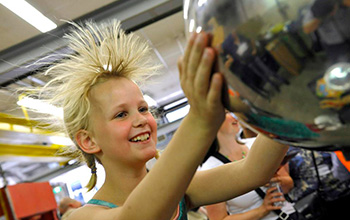Blond girl touching van de graaff causing her hair to stand