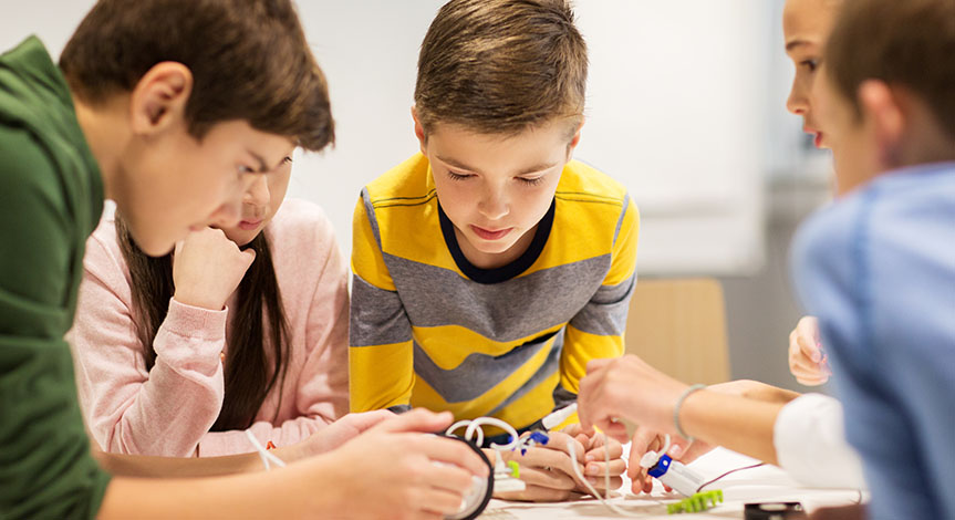 Children building robots around a table