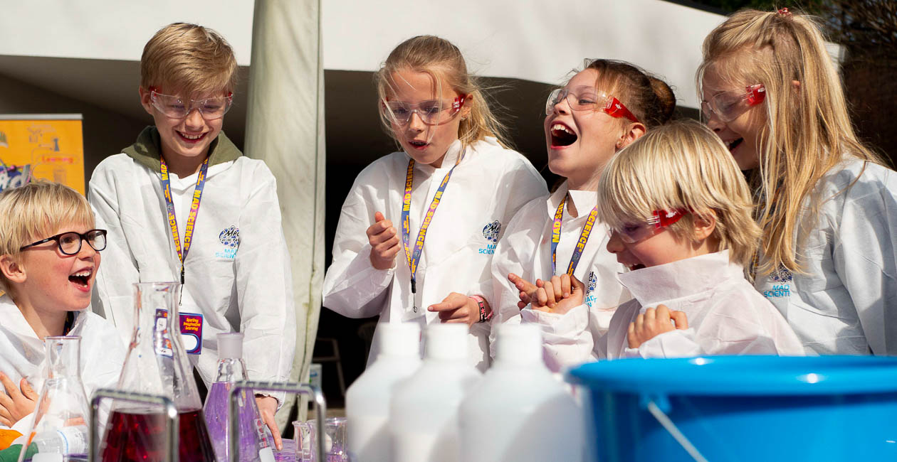 Kids outside laughing, surrounded by science equipment.