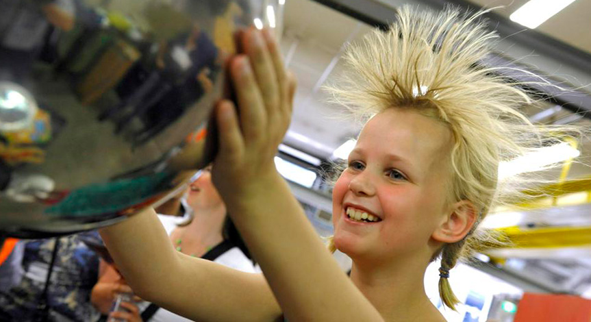 Blond girl touching van de graaff causing her hair to stand