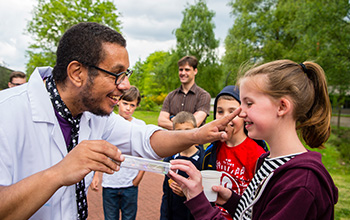 Mad scientist holding tube with girl holding other end while mad scientist touches her nose to transfer electricity