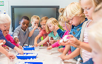 Kids around a table playing with white cotton.