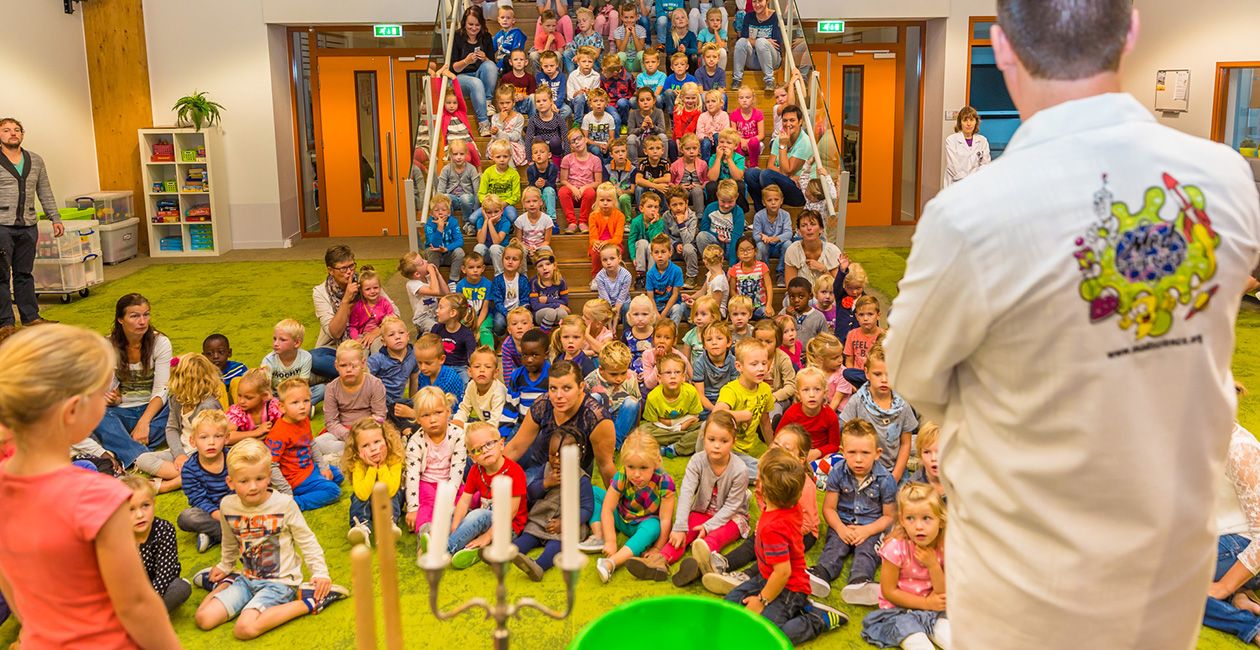 Mad scientist performing in front of kids sitting on the floor and up the stairs